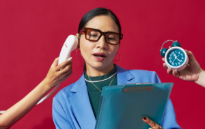 A woman in a blue blazer and glasses stands in front of a red background, holding a clipboard. She looks overwhelmed as one hand holds a phone receiver to her ear, and another hand holds up a blue alarm clock next to her. The woman appears to be multitasking and stressed with the demands of time and communication.